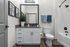 Elegant modern bathroom with sleek vanity, stylish artwork, and inviting shower area.
