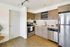 Modern kitchen with sleek stainless steel appliances, warm wood cabinetry, and elegant open shelving, accented with inviting under-cabinet lighting.
