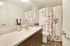 Bright and contemporary bathroom featuring a sleek countertop, elegant floral shower curtain, and modern fixtures.