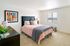 Bright, modern bedroom with stylish decor, featuring a plush bed, vibrant artwork, and a sunlit window.