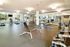 Bright and modern gym with state-of-the-art equipment, featuring treadmills, weight machines, and a yoga area.