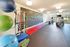 Modern fitness room with vibrant exercise balls, a climbing wall, elliptical machines, and large windows for natural light.