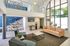 Bright and modern living area featuring a high ceiling, sleek furniture, and large arched windows overlooking greenery.