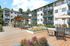 Inviting apartment complex featuring spacious outdoor deck with seating, modern balconies, and lush green surroundings.