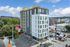 Modern urban apartment building with a sleek design, featuring large windows and bold color accents, located in a vibrant neighborhood.
