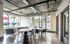 Modern industrial-style apartment lounge with chic exposed ceiling, sleek gray furniture, and large windows allowing natural light.