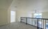 Bright and airy loft space with large windows offering stunning city views, complete with sleek railing and ceiling fan.