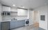 Modern apartment kitchen with sleek cabinetry, stainless steel appliances, and in-unit laundry adjacent to a contemporary bathroom.