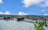 Chic rooftop terrace with vibrant green seating, offering panoramic views of the cityscape and lush greenery under a bright blue sky.