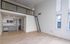 Bright apartment space with high ceilings, a stylish mezzanine, modern kitchen, and large windows overlooking the city.