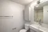 Modern bathroom with sleek white fixtures, stylish lighting, and ample storage space.