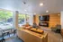 Inviting apartment lounge with modern décor featuring a leather couch, stylish chairs, flat-screen TV, and a cozy fireplace. Large windows offer a bright, natural ambiance and street view.