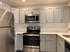 Modern kitchen with sleek stainless steel appliances, elegant light gray cabinets, and a stylish tile backsplash.