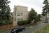 Charming multi-story townhouse surrounded by lush greenery on a quiet residential street, ideal for urban living.