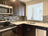 Modern kitchen with sleek dark wood cabinets, stainless steel appliances, and stylish mosaic backsplash.