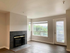 Bright living room with a modern fireplace, large windows, and a serene view, perfect for relaxation.