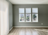 Bright, elegant room with three large windows showcasing scenic views and beautiful hardwood floors.