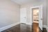 Bright room with elegant hardwood floors, soft beige walls, and a doorway leading to a modern bathroom with white tiles.