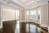 Bright and spacious living area featuring bay windows with city views and elegant dark wood floors.