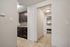 Inviting apartment hallway leading to a cozy bedroom and a sleek kitchen with elegant dark cabinets.
