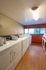 Bright and spacious laundry room with modern washers and dryers, featuring large windows and warm wood flooring.