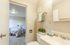 Welcoming bathroom view with a glimpse into a cozy, well-lit bedroom featuring a comfortable bed and soft, inviting decor.