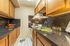 Cozy kitchen with sleek black countertops, wooden cabinetry, and modern appliances, featuring vibrant fruit and stylish spice rack.