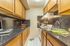 Modern kitchen with sleek black countertops, wooden cabinets, and stainless steel appliances, featuring cozy lighting.