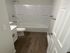 Modern bathroom with elegant wood flooring, pristine white fixtures, and a sleek bathtub for a luxurious feel.