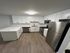 Modern kitchen with sleek stainless steel appliances, white cabinetry, and stylish wood flooring.