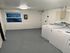 Sleek and bright laundry room with modern washers, white walls, and ample space, offering convenience and practicality.