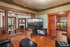 Elegant living room with vintage wooden details, cozy fireplace, and a large TV displaying a cityscape. Natural light floods through the windows, highlighting the intricate ceiling design.