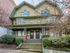 Charming historic home with intricate architectural details and a welcoming front porch, nestled in lush greenery.