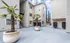 Charming courtyard view with modern apartment exterior, stylish potted palm trees, and convenient mailbox setup.