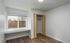 Bright, modern apartment room with sleek hardwood floors, abundant natural light from a large window, and convenient built-in storage solutions.