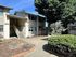 Charming apartment exterior with lush landscaping and inviting entryway under a clear blue sky.