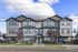 Charming modern townhouse exterior with large windows, fresh siding, and landscaped entryway on a sunny day.