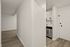 Inviting apartment entrance with sleek modern flooring and a glimpse into a bright kitchen.