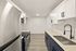 Modern kitchen with sleek stainless steel appliances, elegant white and navy cabinetry, and stylish fixtures on light wood flooring.