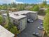 Aerial view of a modern apartment building surrounded by lush greenery, ample parking space, and a serene residential area.