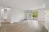 Bright, open living area with elegant wooden flooring and a large sliding door leading to a lush outdoor view.