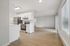 Bright and modern open-concept kitchen and living space with sleek white cabinetry, stainless steel appliances, and inviting hardwood floors.