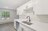 Modern kitchen with sleek white cabinetry, stainless steel appliances, and elegant hardwood flooring, offering a bright and inviting space.