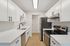 Modern kitchen with sleek white cabinetry, stainless steel appliances, and elegant wood flooring.