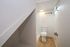 Chic and modern bathroom with a sleek design, featuring hardwood flooring and bright ambient lighting, offering a cozy and efficient space under the stairs.