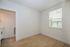 Bright and airy room with elegant wood flooring and a large window, providing abundant natural light.