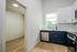 Bright, modern kitchen with navy and white cabinetry, stainless steel appliances, and wood flooring adjacent to a spacious room.
