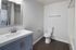 Modern bathroom with sleek vanity and integrated washer-dryer, featuring elegant fixtures and a stylish floor.
