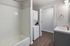 Modern bathroom with sleek vanity, built-in washer and dryer, and elegant wood flooring.