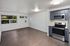 Modern apartment interior with sleek hardwood floors, large windows, and a contemporary kitchen equipped with stainless steel appliances.